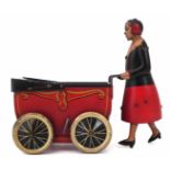 Burnett tin plate clockwork pram, pushed by woman with walking action, stamped 'Burnett Limited,