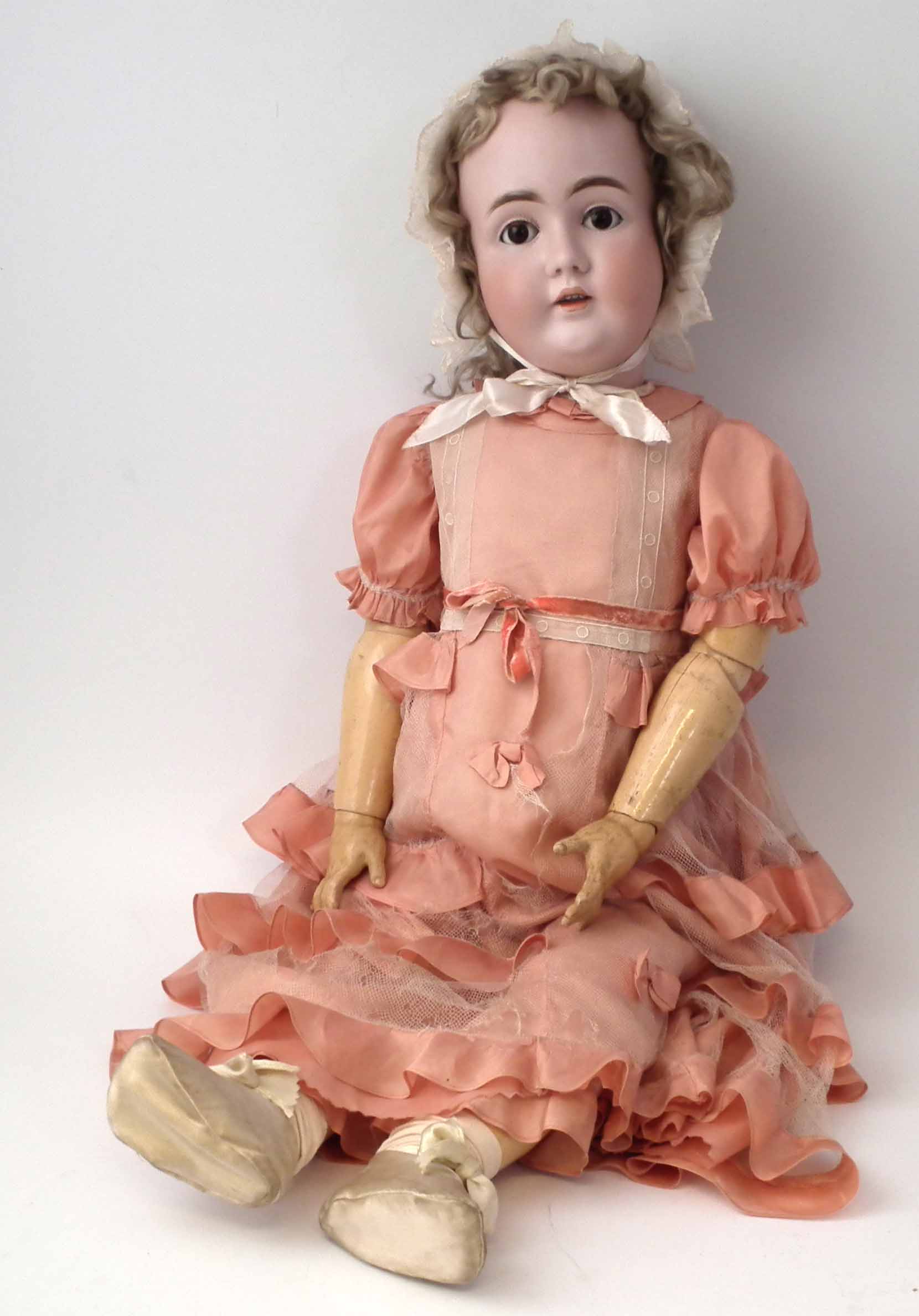 Large bisque head doll attributed to Kestner, with pink lacework dress and lace bonnet, no marks