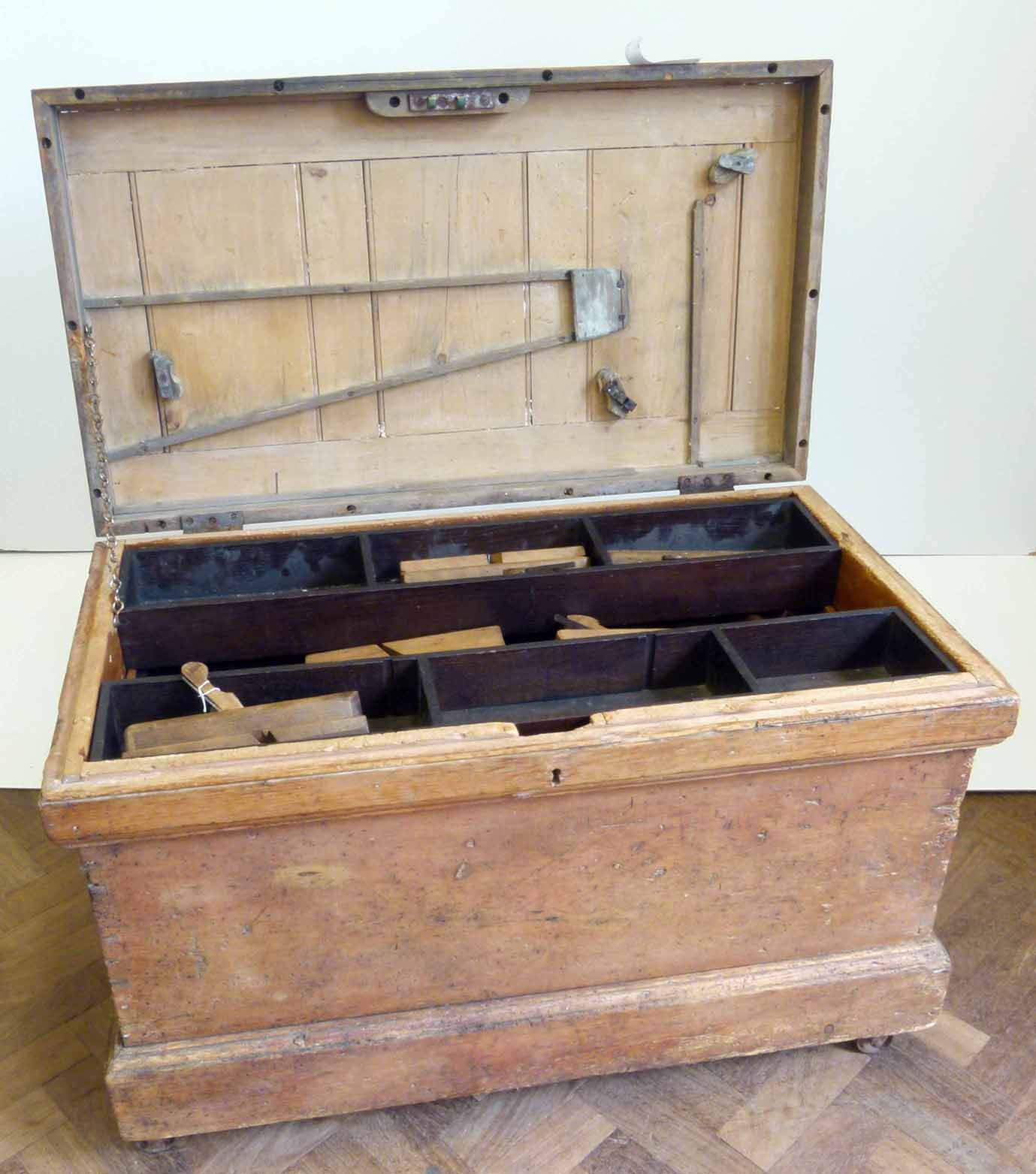 Pine joiners chest, with twin carry handles and raised on four casters, the interior fitted with