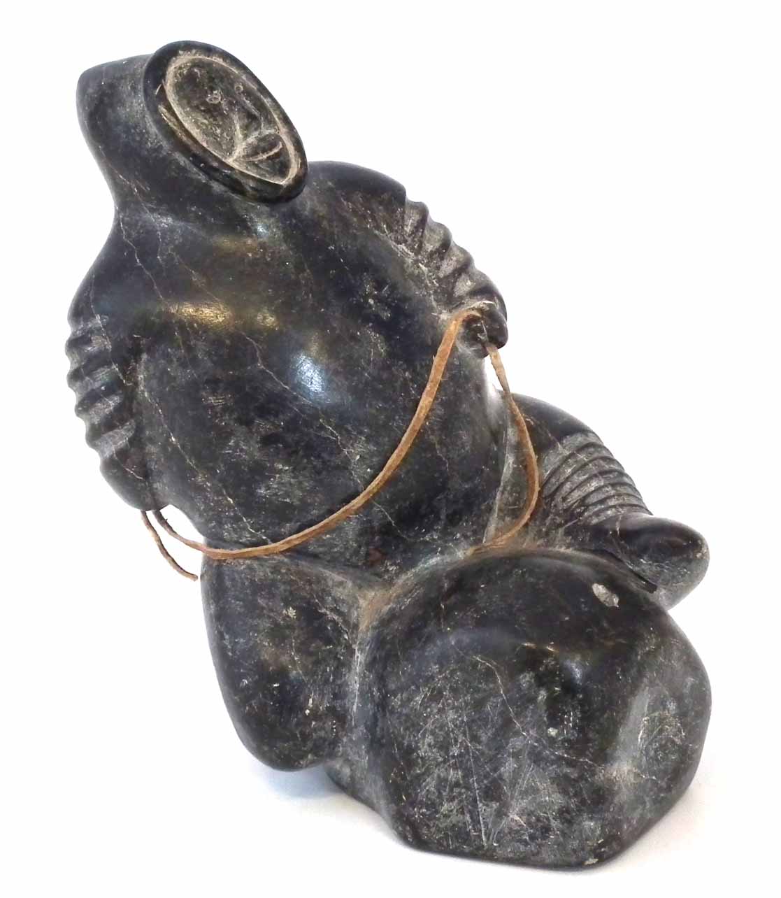 Carved soapstone figure probably Isah Sheeq, depicting an Inuit sitting on a rock, E9774 to base,