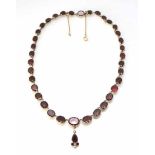 A Victorian yellow gold garnet set riviere necklace with seperate small garnet and seed pearl