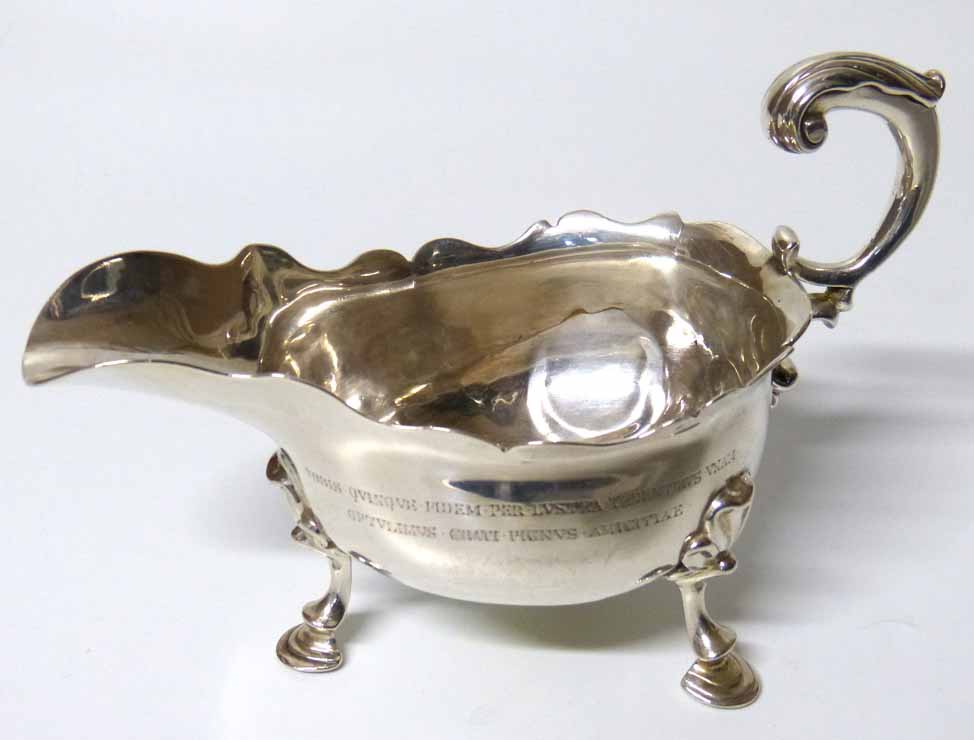 Georgian silver sauce boat of traditional form with curved scroll loop over handle, three pad feet