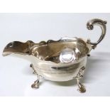 Georgian silver sauce boat of traditional form with curved scroll loop over handle, three pad feet