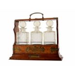 Late 19th century three bottle tantalus, oak frame with brass mounts and decanters with hobnail