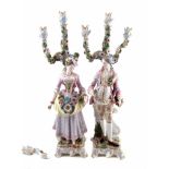 Pair of large continental porcelain table candelabra, modelled as a lady and gentleman collecting