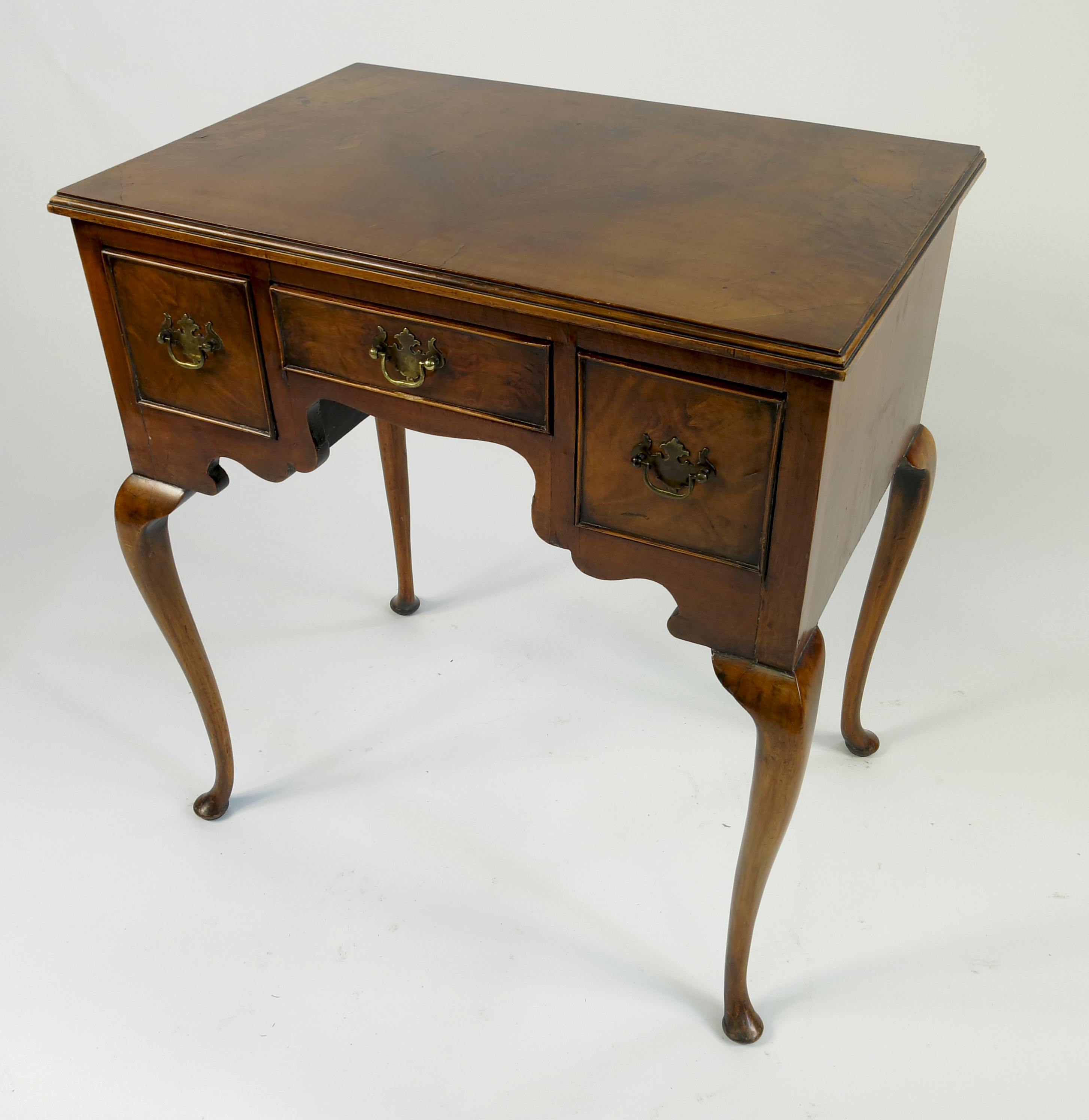 A Georgian style walnut lowboy, with half veneered top fitted with three drawers,
