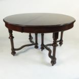 A circular extending dining table, raised on turned legs, united by wavy stretchers,