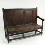 An 18th century oak settle, having a plank panel back, solid seat, open arms,