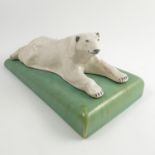An Ashtead Potters model, of a polar bear lying on a green rectangular base,