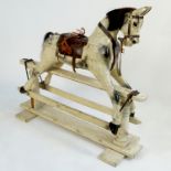 A part carved dapple grey wooden rocking horse, raised on swing frame,