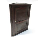 A 19th century oak corner cupboard, with panel door opening to reveal two shaped shelves,