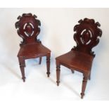A pair of Victorian mahogany hall chairs, with a cartouche back and solid seat,