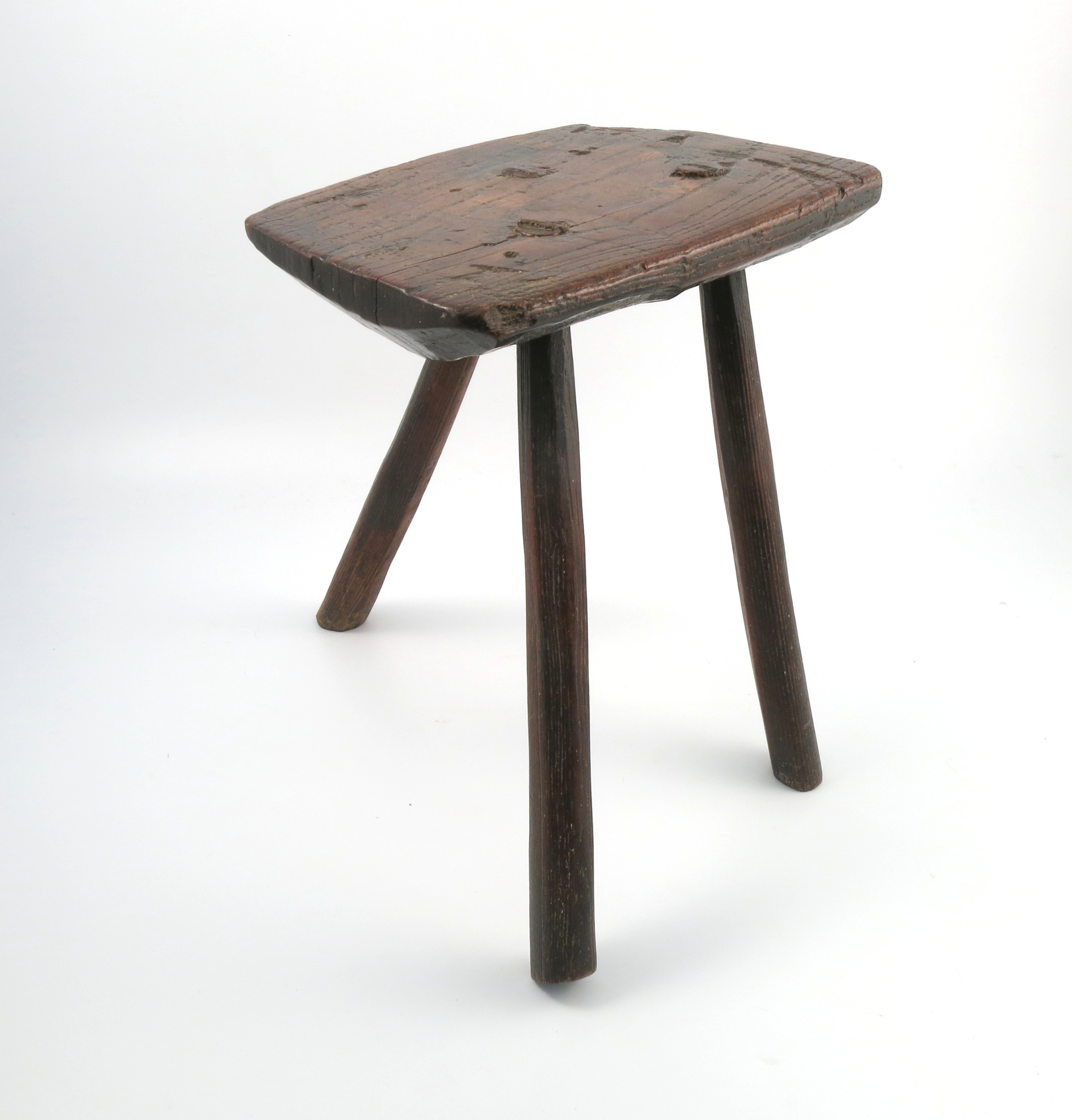 An Antique primitive stool, the rectangular top raised on three legs, 14ins x 9ins x 16.