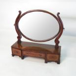 A 19th century dressing table mirror, the oval mirror raised on shaped end supports,