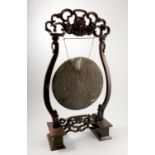 An Oriental gong, the brass circular gong suspended from a hardwood stand,
