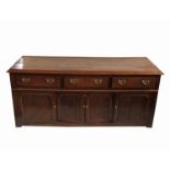 An oak cupboard dresser base, fitted with three drawers with four cupboard doors below,