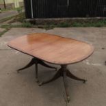 A reproduction twin pillared mahogany dining table,