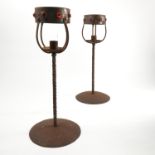 A pair of metal candle stands, with circular glass set bands,