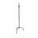 An antique iron pricket candle stand, the octagonal column raised on a tripod base,