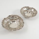 A pair of pierced silver dishes, with embossed and pierced edge, raised on ball feet,