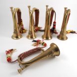 Five brass military bugles, four with military badges,