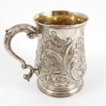 A Georgian silver mug, the baluster shaped body embossed with flowers, scrolling leaves and vine,