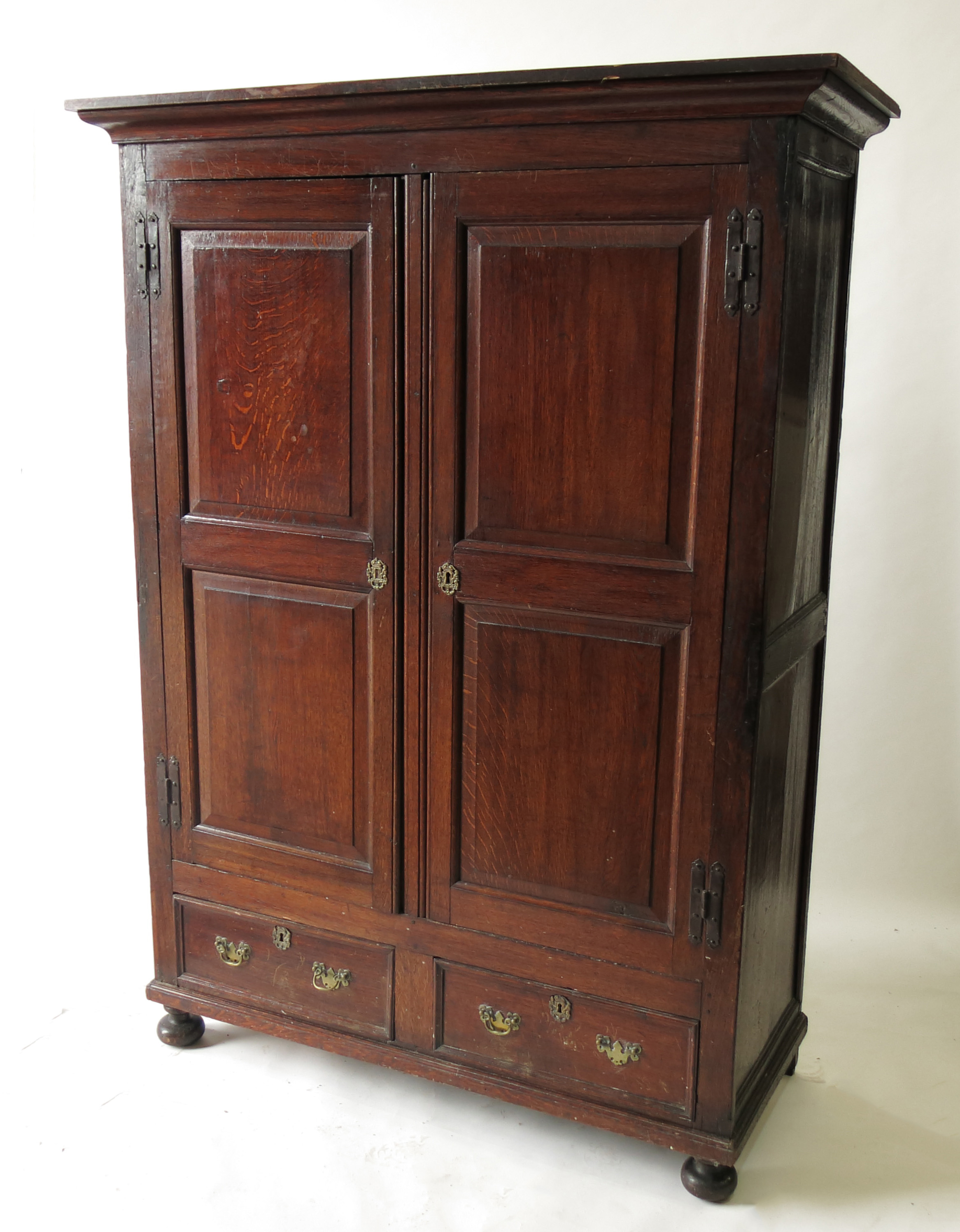 An 18th century style panelled oak cupboard, with two doors, each over a short drawer to the base,