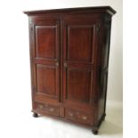 An 18th century style panelled oak cupboard, with two doors, each over a short drawer to the base,