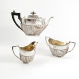 A silver three piece tea set, of oval form with gadrooned lower body, engraved with initials,