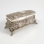 A silver dressing table box, of rectangular form, heavily embossed with scrolls and flower heads,