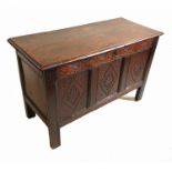 An Antique oak coffer, with three carved panels to the front, below a plain rising lid,