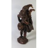 An African Carved Wooden Figure of a travelling man with basket and giant land snail attached and