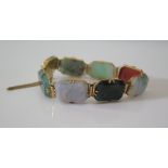 A Jade Bracelet in a high carat gold setting, mounted with seven coloured specimens, 24.7 g