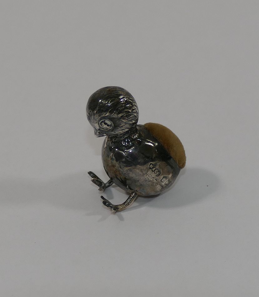 A miniature silver pin cushion in the form of a chick in an egg, Birmingham 1910,