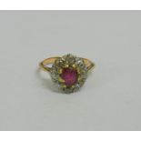 An 18 carat gold ruby and diamond oval cluster ring, the oval mixed cut ruby approximately 0.