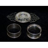 A silver two handled tea strainer, Birmingham 1920, 11cm wide, and two napkin rings,