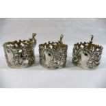 Three late Victorian silver glass or cup holders with formal embossed and pierced decoration,