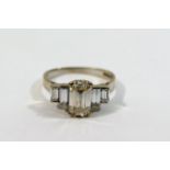 An Art Deco style white gold diamond five stone ring, the centre emerald cut stone approximately 1.