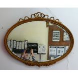 An oval gilt gesso framed bevelled edge wall mirror, with beaded rim and ribbon surmount,