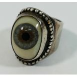 An unusual silver ring set with a glass eye in rub-over mount with beaded rim,