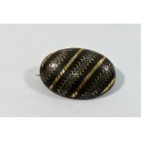 A Victorian pique oval brooch, the tortoiseshell cabochon inlaid with ornate gold and silver bands,