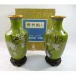 A pair of 20th century Chinese green ground cloisonne vases, decorated with birds amongst blossom,