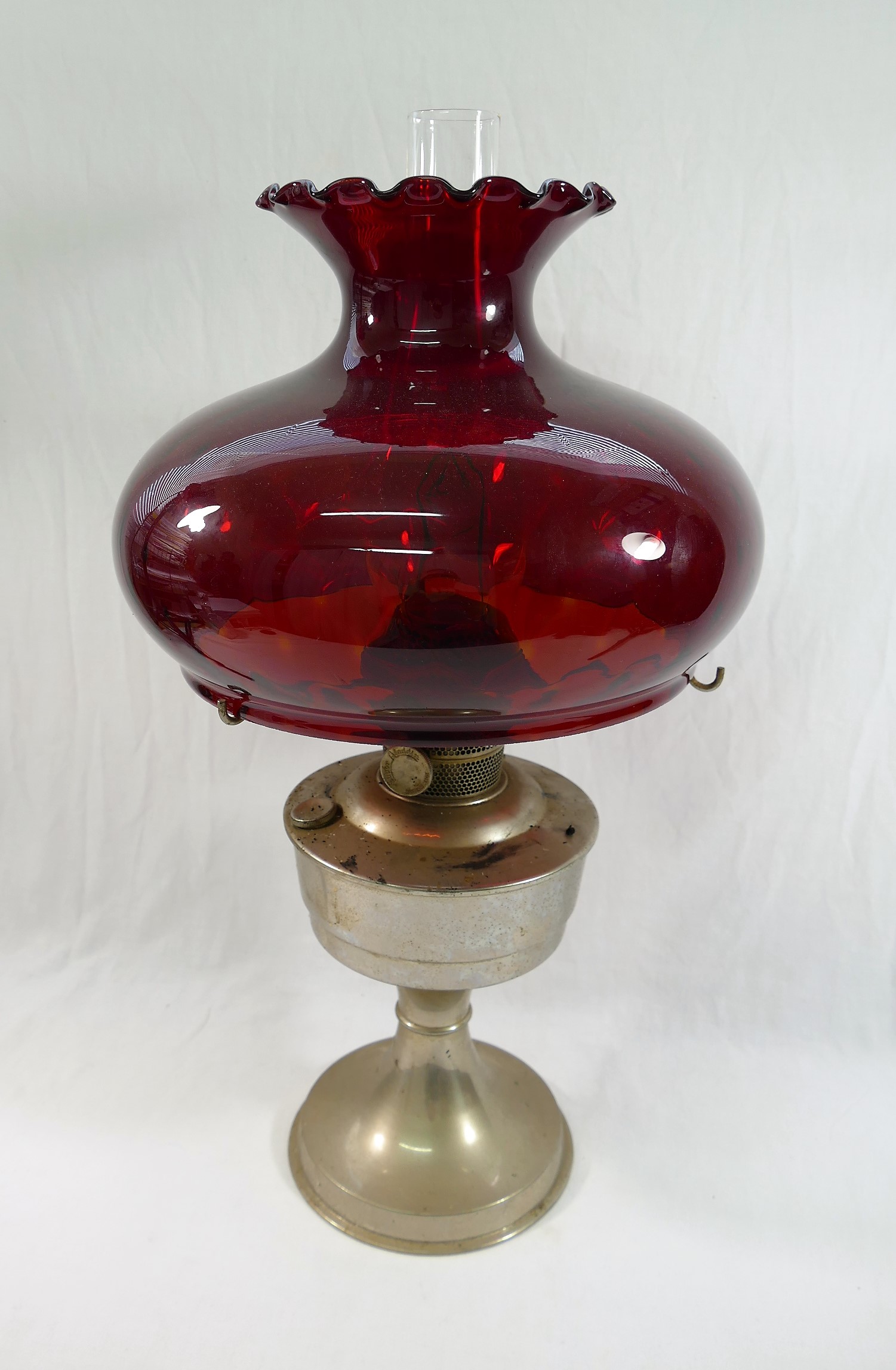 A 20th century 'Super Aladdin' oil lamp with a large ruby glass shade,