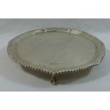 A small silver circular tray, with gadrooned rim, raised on claw feet, Sheffield 1923, 12.