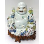 A early 20th Century porcelain Buddha and boys group with original carved hardwood stand, height