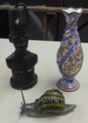 An ornate enamel decorative vase, a carved wood figure of an African and a stoneware snail model.