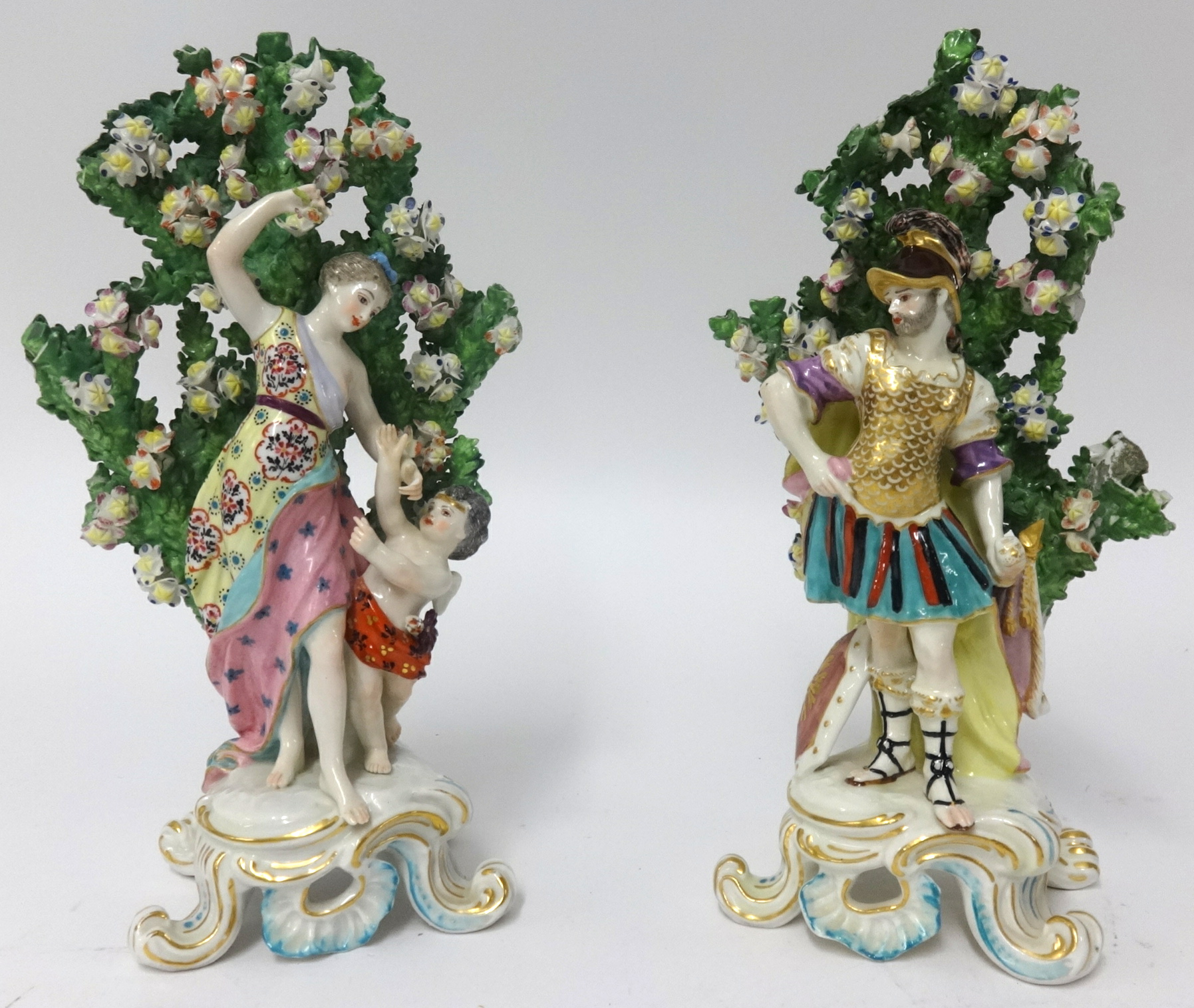 Pair of porcelain figurative groups with bocage depicting a mother and a winged putti and a