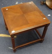 A reproduction mahogany nest of tables with drop flaps and glass covers.