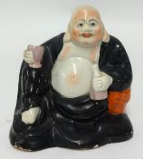 An early 19th century Staffordshire pearlware figure of Hotei, holding a bottle and glass and clad