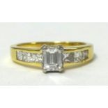 18ct diamond set ring with centre emerald cut stone and princess cut diamonds to the shoulders